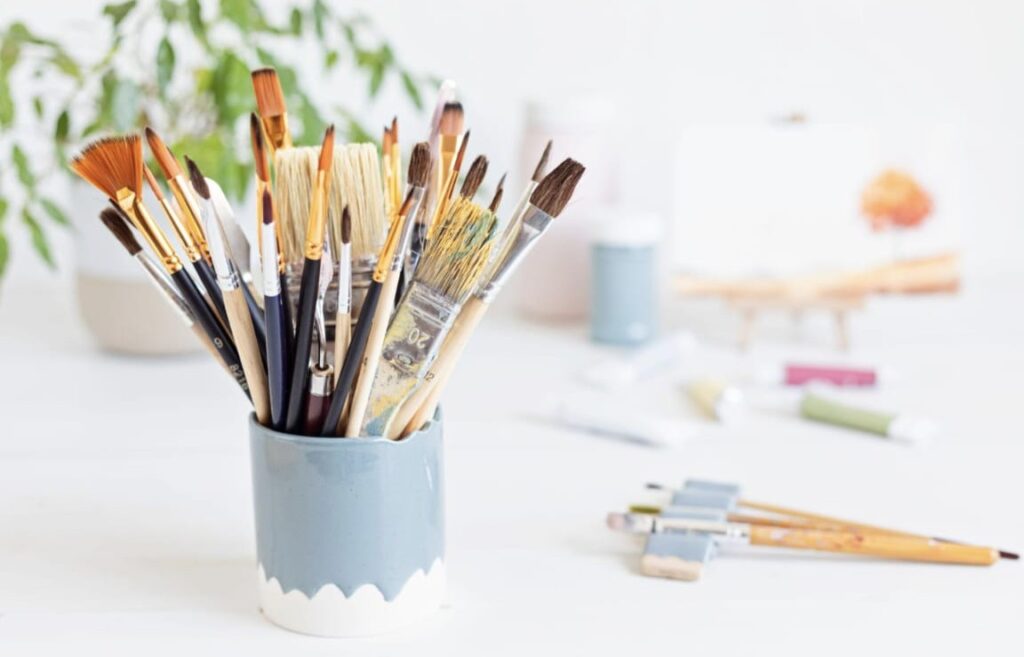 תמונה של כוס עם מכחולים צמח ועוד מכחולים מפוזרים